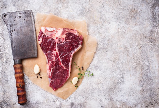 Chuletón de carne cruda con cuchillo de carnicero