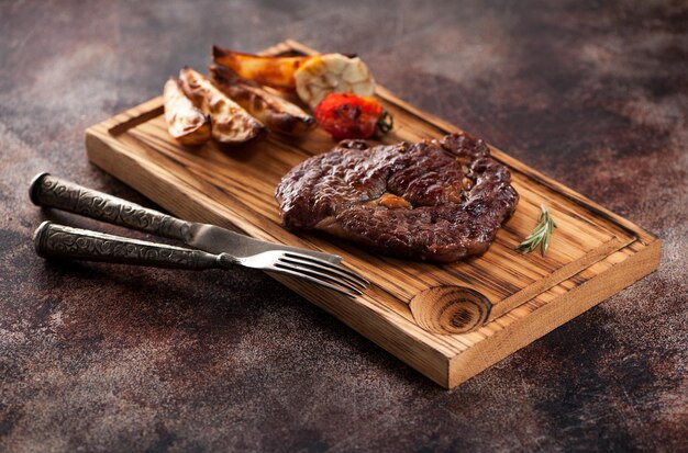 Chuletón de ternera a la parrilla con patatas fritas sobre un fondo marrón oxidado