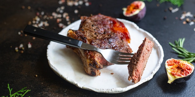 Chuletón de ternera a la parrilla sobre una placa blanca.