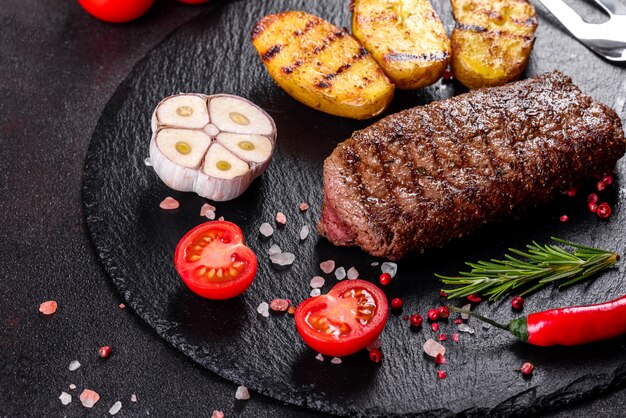 Chuletón de ternera con patatas, cebolla y tomates cherry. Jugoso bistec con mantequilla aromatizada