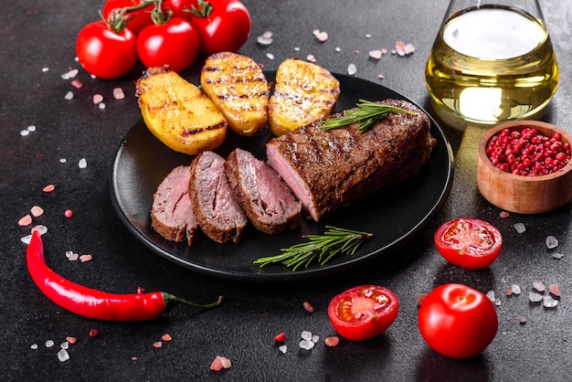 Chuletón de ternera con patatas, cebolla y tomates cherry. Jugoso bistec con mantequilla aromatizada