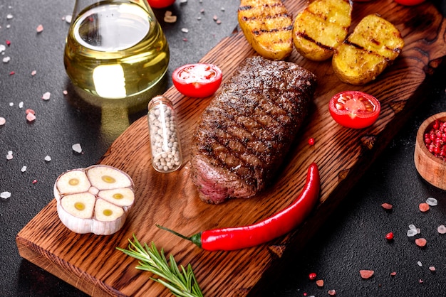 Chuletón de ternera con patatas, cebolla y tomates cherry. Jugoso bistec con mantequilla saborizada