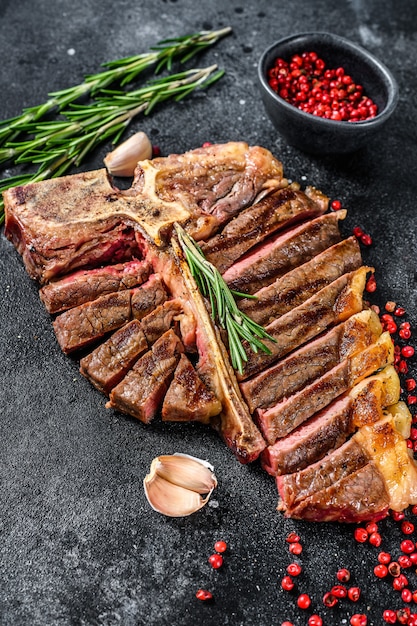 Chuletón de ternera a la plancha en rodajas. Carne de res cocida en tbone. Fondo negro. Vista superior.