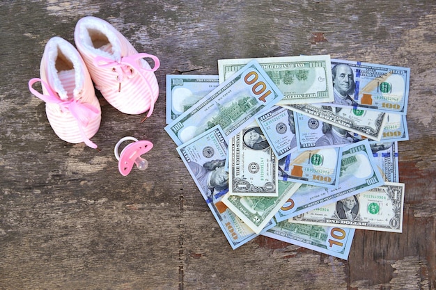 Chupetes rosas y zapatos para niños en el fondo del dinero.