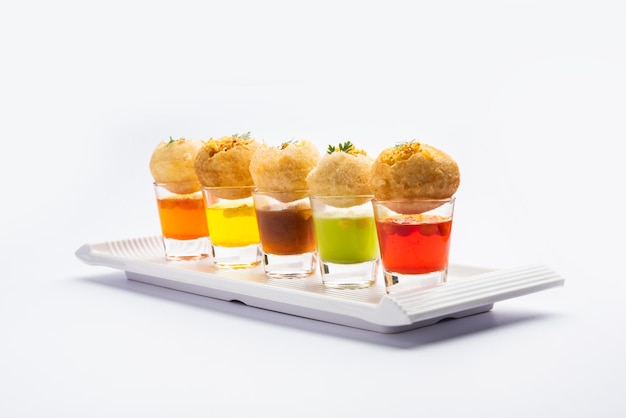 Chupito Panipuri o Golgappa Shots de diferentes sabores de agua servidos en vasos pequeños con un bocadillo de entrada indio puri relleno