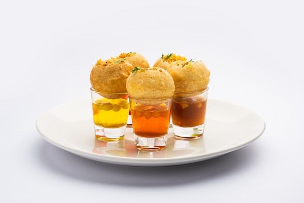 Chupito Panipuri o Golgappa Shots de diferentes sabores de agua servidos en vasos pequeños con un bocadillo de entrada indio puri relleno