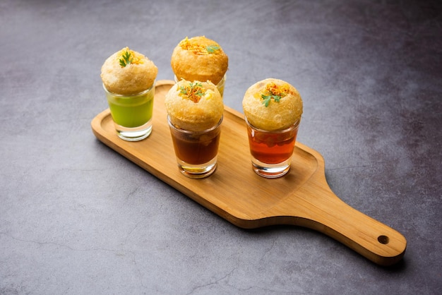 Chupito Panipuri o Golgappa Shots de diferentes sabores de agua servidos en vasos pequeños con un bocadillo de entrada indio puri relleno