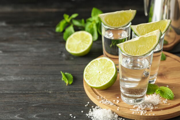 Chupitos de tequila con rodajas de limón, sal y menta sobre madera