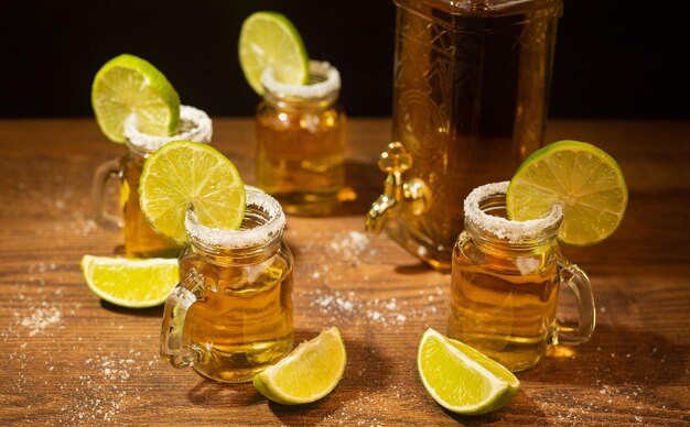 Chupitos de tequila servidos en frascos con sal y limón sobre mesa de madera