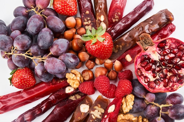 Churchkhela mix, frutas, bayas y nueces sobre una mesa blanca, dulces caucásicos