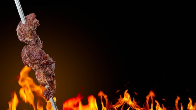 Foto churrasco brasileiro tradicional carne de churrasco no espeto com fogo no fundo e área de texto
