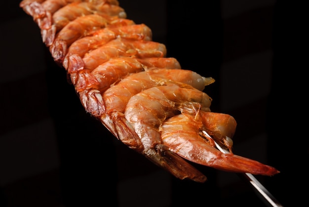 Churrasco de camarão no espeto sobre fundo preto gastronomia brasileira