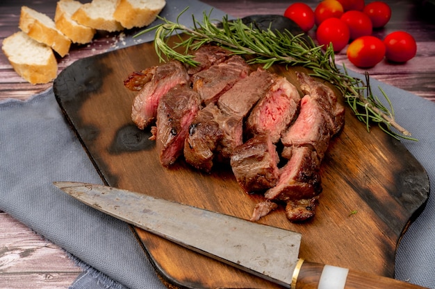 Churrasco de carnes cortadas em pedaços em tábua de madeira, em ambiente rústico. Vista aérea