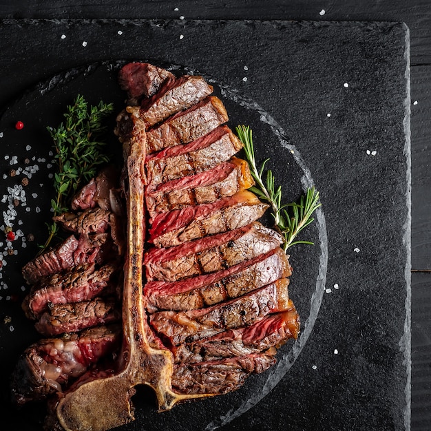 Foto churrasco envelhecido a seco bife de porterhouse bife t-bone fatiado com um pedaço grande de filé com ervas e sal