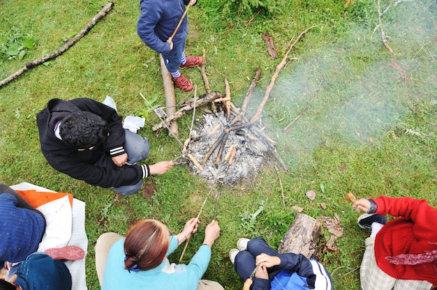 Churrasco na natureza, grupo de pessoas preparando salsichas em chamas