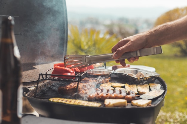 Churrasco no fim de semana Salsichas bife queijo e legumes na grelha a gás Ao ar livre