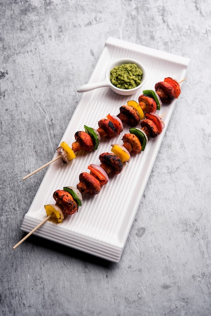 Churrasco ou cogumelo tandoori tikka, servido em prato com chutney verde e ketchup. foco seletivo