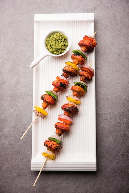 Churrasco ou cogumelo tandoori tikka, servido em prato com chutney verde e ketchup. foco seletivo