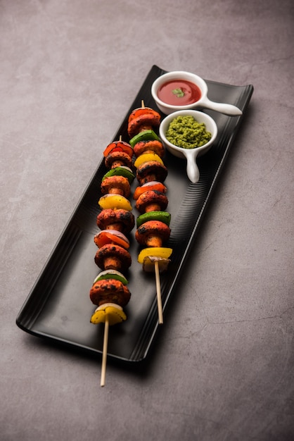 Churrasco ou Cogumelo Tandoori Tikka, servido em prato com chutney verde e ketchup. foco seletivo