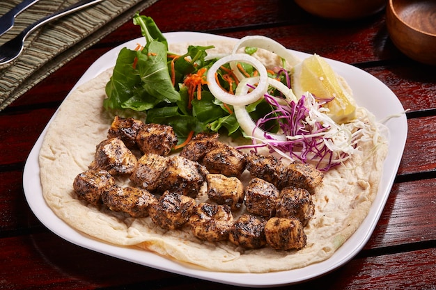 Churrasco picante frango Tikka boti kabab com pão limão e salada servido em prato isolado na vista lateral da mesa de comida do oriente médio