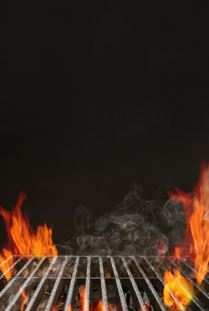 Churrasqueira vazia quente com fogo flamejante brilhante, carvão de brasa e fumaça em fundo preto. Aguardando a colocação de sua comida. Conceito de churrasco. Feche, copie o espaço