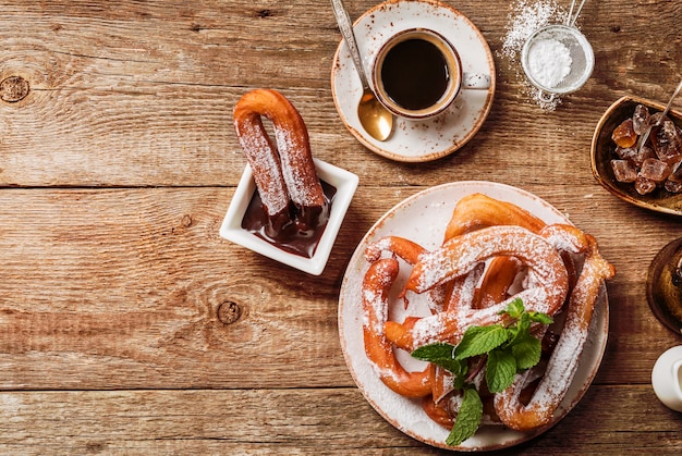 Churros café y chocolate caliente en la vista superior de la mesa de madera