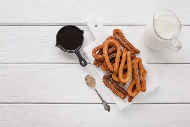 Churros caseiros com chocolate em um fundo branco de madeira