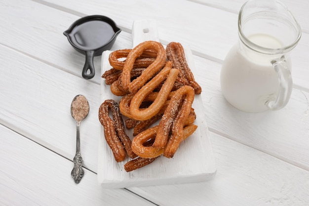 Churros caseiros com chocolate em um fundo branco de madeira