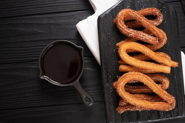 Churros caseiros com chocolate em um fundo rústico de madeira escuro