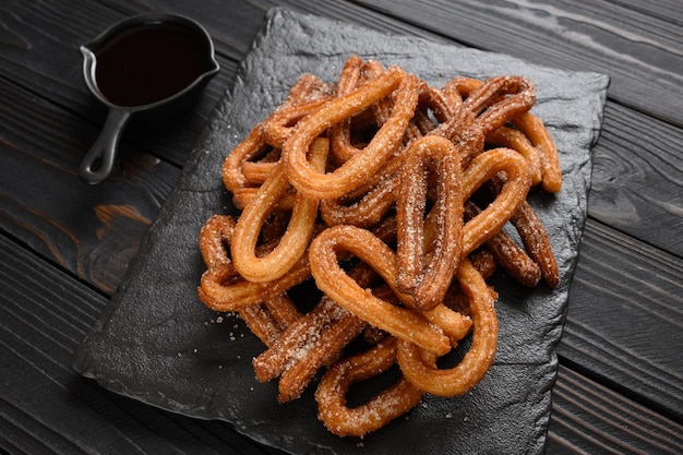 Churros caseiros com chocolate em um fundo rústico de madeira escuro