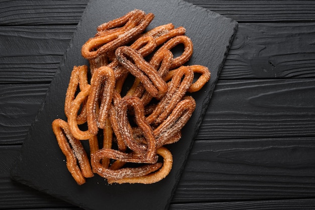 Churros caseiros em um fundo preto de madeira