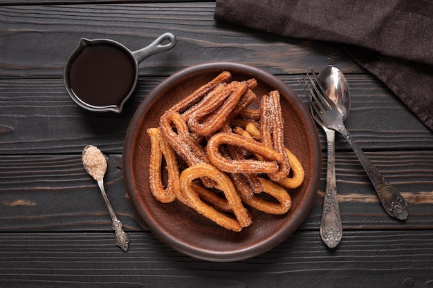 Churros caseros con chocolate sobre un fondo rústico de madera oscura