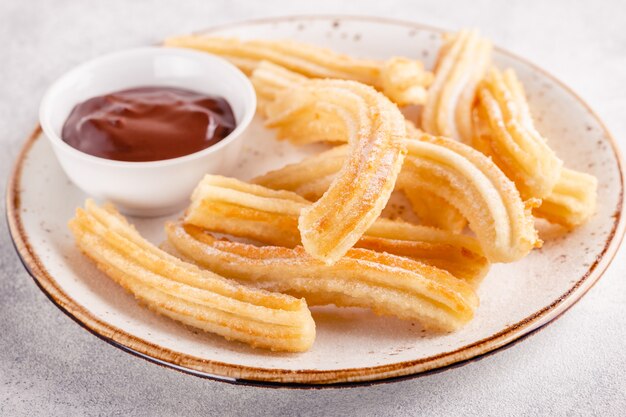 Churros com açúcar de confeiteiro e calda de chocolate.