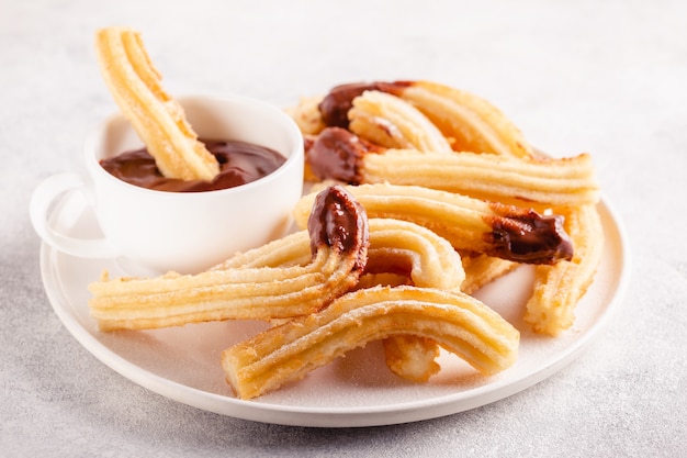 Churros com açúcar de confeiteiro e calda de chocolate.