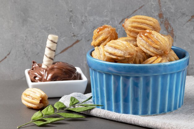 Churros de doce de leite em uma tigela azul e servido com wafer de avelã.