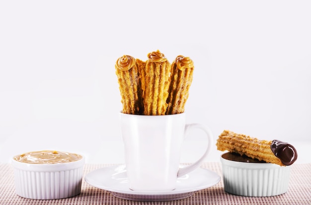 Churros in einem Becher traditionelle gebratene Süßigkeit aus Lateinamerika, Brasilien, Kolumbien, Vereinigte Staaten und Portugal, serviert mit oder ohne Füllung, bestreut mit Zuckerkopienraum