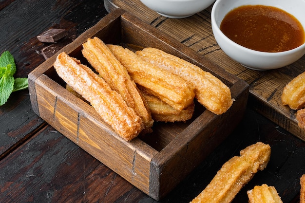 Churros mit Puderzucker bestreut, auf altem dunklem Holztischhintergrund