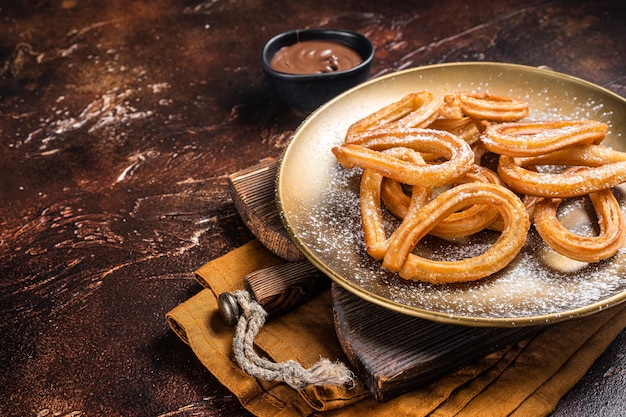 Churros de postre español con chocolate picante caliente Fondo oscuro Vista superior Espacio de copia