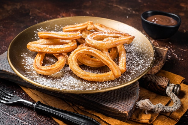 Churros de postre español con chocolate picante caliente Fondo oscuro Vista superior