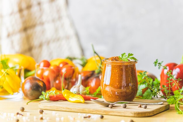 Chutney de salsa picante de ciruela enlatada natural casera con chile o tkemali en un tarro de vidrio sobre una mesa de madera con ingredientes Enfoque selectivo