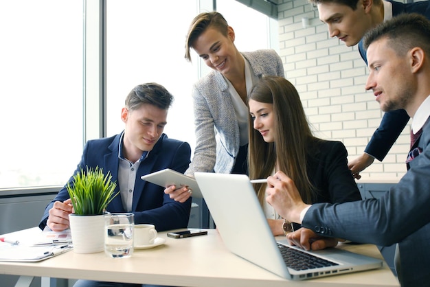 Chuva de ideias. Grupo de empresários, olhando para o laptop juntos. Uma mulher de negócios olhando para a câmera