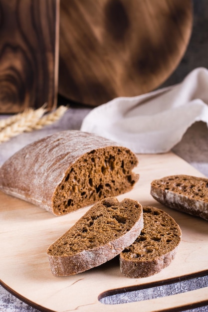 Ciabatta de centeio fatiado em uma tábua de cortar sobre a mesa Cozimento caseiro Visão vertical