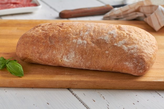 Foto ciabatta ist ein italienisches weißbrot aus weizenmehl wasser salz hefe olivenöl auf weißem holzhintergrund