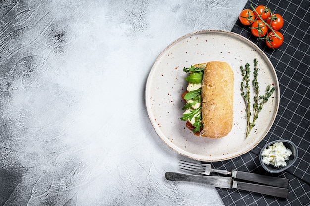 Ciabatta-Sandwich mit frischem Ziegenkäse, Birnenmarmelade und Rucola. Grauer Hintergrund. Draufsicht. Platz für Text