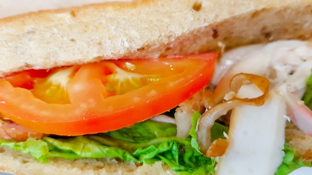 Ciabatta-Sandwich mit Salat, Hühnchen und Käse auf einem Holztisch.