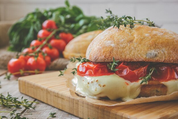 Ciabatta-Sandwich mit Tomaten, Kräutern und Öl auf geröstetem Knoblauchkäsebrot. Getönt.