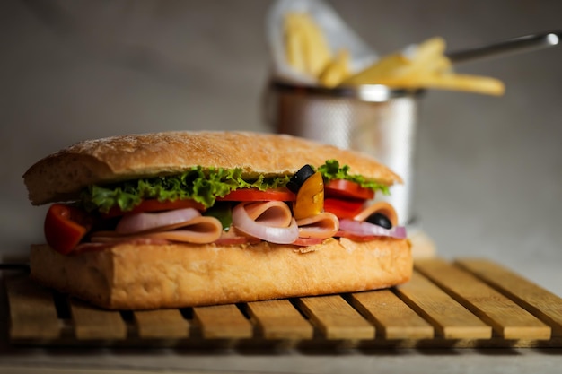 Foto ciabatta smoked ham sandwich isolado em madeira com molho de maionese e batatas fritas vista lateral do balde de fast food italiano em fundo cinza