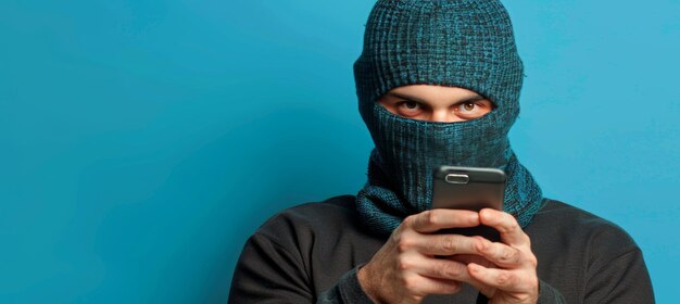 Foto cibercriminoso masculino de traje preto e balaclava segurando telefone ilustrando o conceito de fraude telefônico