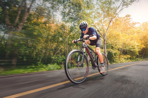 Ciclismo Bicicleta de montaña Ciclismo MTB en la carretera sombreada con bosque. Atleta de ciclismo de montaña mira la naturaleza salvaje en la montaña. Deporte extremo y MTB, bicicleta de montaña cuesta abajo del concepto de movimiento.