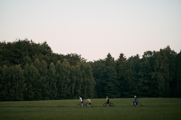 Ciclismo a campo traviesa en el bosque gente caminando con bicicletas en el campo